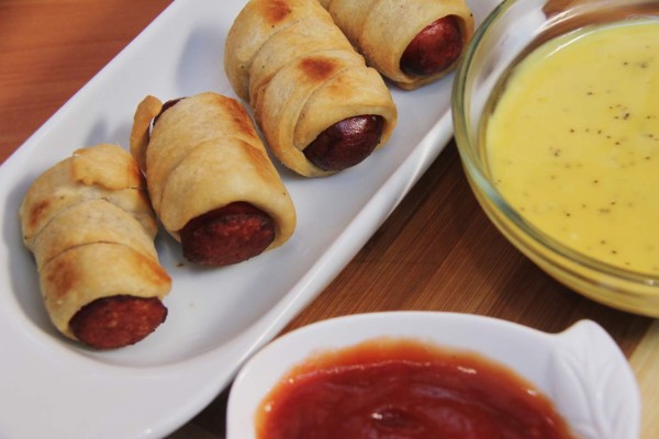 Sirva los rollitos de hot dog con diferentes tipos de aderezos.