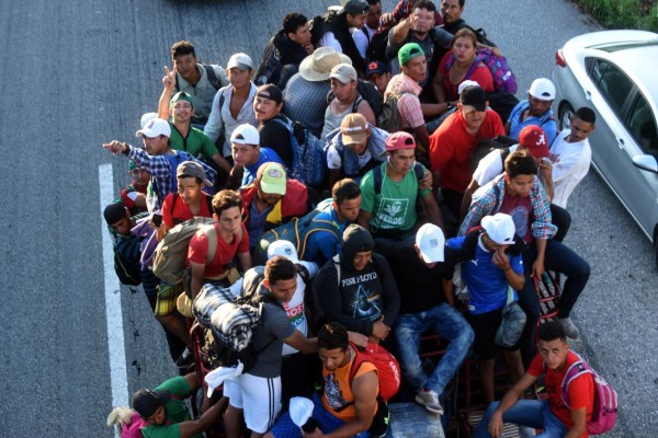 Honduran migrants heading in a caravan to the US, travel aboard a truck in Mapastepec on their way to Pijijiapan Chiapas state, Mexico, on October 25, 2018. - Thousands of Central American migrants crossing Mexico toward the United States in a caravan have resumed their long trek, walking about 12 hours to their next destination. (Photo by Johan ORDONEZ / AFP)