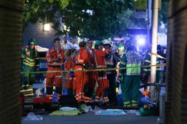 Paramedics working at the scene ned to a huge fire at Grenfell Tower, in west London on June 14, 2017. The massive fire ripped through the 27-storey apartment block in west London in the early hours of Wednesday, trapping residents inside as 200 firefighters battled the blaze. Police and fire services attempted to evacuate the concrete block and said 'a number of people are being treated for a range of injuries', including at least two for smoke inhalation. / AFP PHOTO / Daniel Leal-Olivas