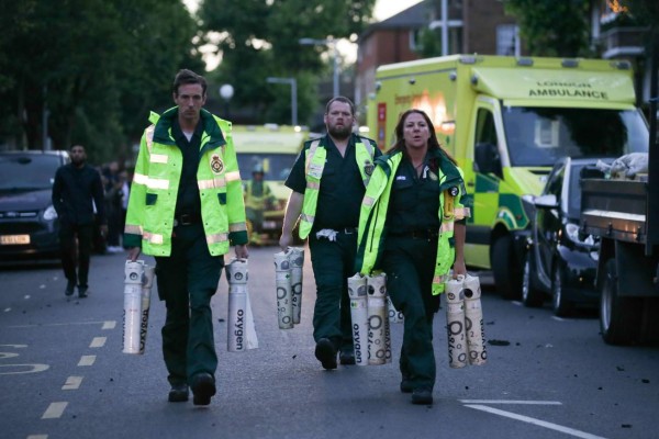 Paramedics arrive with oxygen as a huge fire engulfs the Grenfell Tower early June 14, 2017 in west London. The massive fire ripped through a 27-storey apartment block in west London in the early hours of Wednesday, trapping residents inside as 200 firefighters battled the blaze. Police and fire services attempted to evacuate the concrete block and said 'a number of people are being treated for a range of injuries', including at least two for smoke inhalation. / AFP PHOTO / Daniel Leal-Olivas