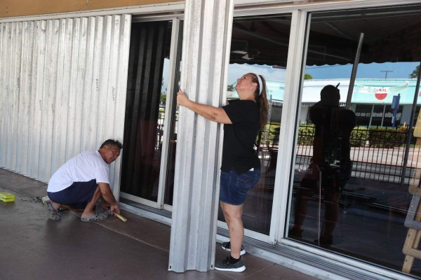STUART, FLORIDA - AUGUST 01: David Terrazas and Andrea Hagopian (L-R) put shutters over the sliding glass doors at Maria's Restaurant as Hurricane Isaias approaches on August 01, 2020 in Stuart, Florida. The hurricane is expected to brush past the east coast of Florida within the next 24 hours. Joe Raedle/Getty Images/AFP== FOR NEWSPAPERS, INTERNET, TELCOS & TELEVISION USE ONLY ==