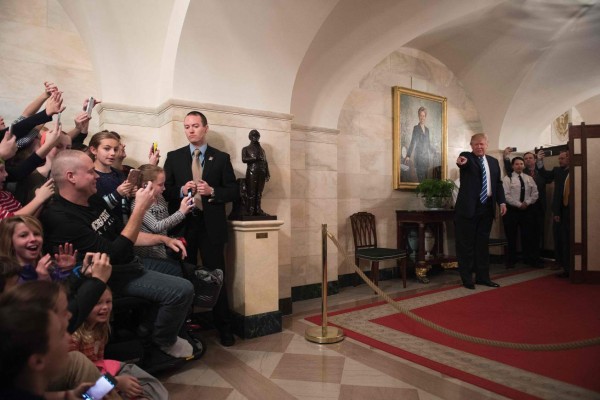 US President Donald Trump points to child in the crowd as he surprises visitors during the official reopening of public tours at the White House in Washington, DC, March 7, 2017. / AFP PHOTO / JIM WATSON