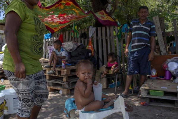 Venezuelan ten-month-old Maria (C) remains near her parents on the side of a road in Boa Vista, Roraima state, Brazil, on August 23, 2018. Desperate Venezuelans fleeing the country's crisis continue to cross the Brazilian border, despite the violent anti-migrant riot that took place last week in the border town of Pacaraima. / AFP PHOTO / Mauro Pimentel