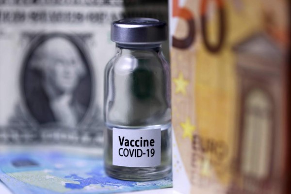 This illustration picture shows a vial reading 'Covid-19 Vaccine' with dollar and euro banknote, in Paris, on November 26, 2020 . (Photo by JOEL SAGET / AFP)