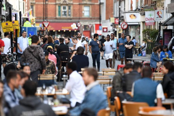 Customers sit outside re-opened bars in Soho in London on July 5, 2020, as the Soho area embraces pedestrianisation in line with an easing of restrictions during the novel coronavirus COVID-19 pandemic. - Pubs in England reopened this weekend for the first time since late March, bringing cheer to drinkers and the industry but fears of public disorder and fresh coronavirus cases. (Photo by DANIEL LEAL-OLIVAS / AFP)