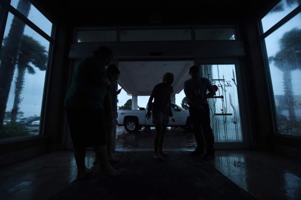 Local residents watch the storm in the dark after a citywide power failure as Hurricane Harvey hit Corpus Christi, Texas on August 25, 2017. Harvey on Friday further intensified into a dangerous category four storm, just hours before it was due to slam into the Texas coast, US meteorologists said. / AFP PHOTO / MARK RALSTON