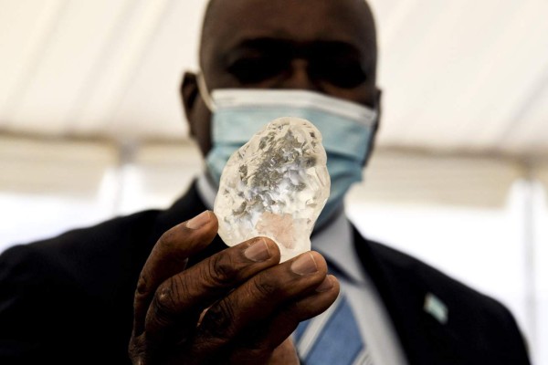 Botswana President Mokgweetsi Masisi (R) holds a gem diamond in Gaborone, Botswana, on June 16, 2021. - Botswanan diamond firm Debswana said on June 16, 2021 it had unearthed a 1,098-carat stone that it described as the third largest of its kind in the world.The stone, found on June 1, 2021 was shown to President Mokgweetsi Masisi in the capital Gaborone. (Photo by Monirul Bhuiyan / AFP)