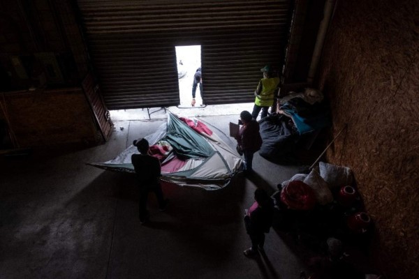 Migrants travelling in the Central American caravan hoping to reach the United States, are being relocated in a warehouse to be used by migrants who were sleeping in the streets as a temporary shelter, in Tijuana, Baja California State, Mexico, on December 14, 2018. - A seven-year-old Guatemalan girl died of dehydration and exhaustion in the custody of US border agents last week, on December 8, as President Donald Trump struggles to deter a tide of migrants fleeing poverty and violence in Central America -- and battles with Congress for a budget to build a massive wall across much of the US-Mexico frontier. (Photo by GUILLERMO ARIAS / AFP)