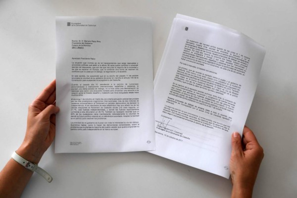 A woman holds a copy of the letter sent by Catalan regional government president Carles Puigdemont to Prime Minister Mariano Rajoy on October 16, 2017 in Barcelona.Madrid gave Catalonia's separatist leader three more days to 'return to legality' after he refused to say whether he would follow through on a threat to declare independence from Spain. Responding to an initial deadline set by the central government, Carles Puigdemont sent a letter early on October 16, 2017 calling for talks with Prime Minister Mariano Rajoy 'as soon as possible' amid Spain's worst political crisis in decades. But he stopped short of giving a definitive 'yes or no' as demanded by Madrid after his ambiguous independence speech last week, and Spain gave him until October 19, 2017 to clarify. / AFP PHOTO / LLUIS GENE