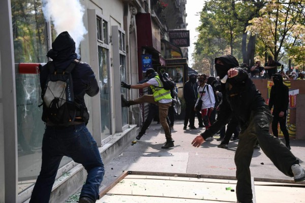 Masked protesters smash the window of a shop during clashes on the sidelines of a May Day demonstration in Paris, on May 1, 2019. - Paris riot police fired teargas as they squared off against hardline demonstrators among tens of thousands of May Day protesters, who flooded the city in a test for France's zero-tolerance policy on street violence. (Photo by Anne-Christine POUJOULAT / AFP)