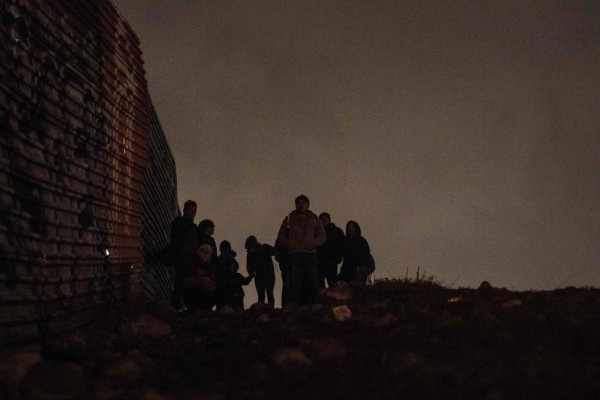 A group of Central American migrants wait beside the US-Mexico border fence, before attempting to cross from Tijuana to San Diego in the US on New Year's Eve, as seen from Tijuana, Baja California state, Mexico on December 31, 2018. - Around 100 Central American migrants made a failed attempt on New Year's Eve to cross over from Mexico into the United States. As night fell and people on both sides of the frontier prepared to celebrate New Year's Eve, the migrants tried to cross over but at least two smoke bombs were hurled and they ultimately held back. (Photo by Guillermo Arias / AFP)