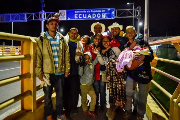 Members of Venezuelan migrant families Mendoza Landinez and Lomelly pose for a photo at the Rumichaca International Bridge, in the border between Ipiales in Colombia, and Tulcan in Ecuador, on August 23, 2018.On foot, by bus, on the backs of juddering trucks, like tens of thousands of others they slogged for days along the Pan-American highway through Colombia and Ecuador. Grubby and sleepless, their goal was to reach Peru, a sanctuary of sorts for a desperate Venezuelan family. Exhausted and swept by the endless wash of traffic noise on the highway's shoulder, the Mendoza Landinez family had the additional pressure of a deadline: to enter Peru before new rules required them to produce a passport. / AFP PHOTO / Luis ROBAYO