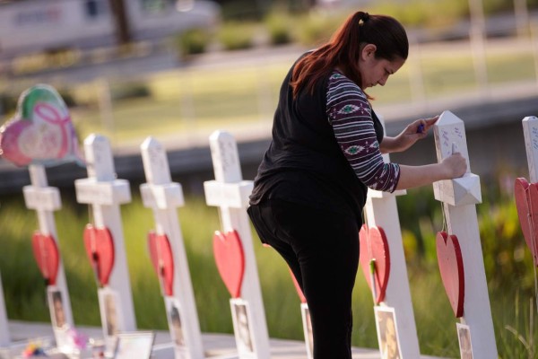 ORLANDO, FL - JUNE 17: A woman writes a note on a cross at a memorial with wooden crosses for each of the 49 victims of the Pulse Nightclub, next to the Orlando Regional Medical Center, June 17, 2016 in Orlando, Florida. The shooting at Pulse Nightclub, which killed 49 people and injured 53, is the worst mass-shooting event in American history. Drew Angerer/Getty Images/AFP== FOR NEWSPAPERS, INTERNET, TELCOS & TELEVISION USE ONLY ==