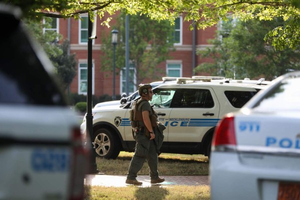 A medic walks between police cars after a shooting on the campus of University of North Carolina Charlotte in University City, Charlotte, on April 30, 2019. - Six people were shot, two of them died on the University of North Carolina Charlotte campus. One person was taken into custody, according to police sources. (Photo by Logan Cyrus / AFP)