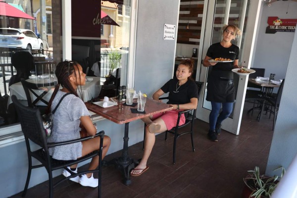 STUART, FLORIDA - MAY 04: Brigitte Staples serves Crescent Wigfall (L) and Lily Garrecht as they sit at the Spritz City Bistro, as the state of Florida enters phase one of the plan to reopen the state on May 04, 2020 in Stuart, Florida. Restaurants, retailers, beaches and some state parks reopen today with caveats, as the state continues to ease restrictions put in place to contain COVID-19. The counties of Palm Beach, Broward and Miami Dade continue to have their restrictions in place. Joe Raedle/Getty Images/AFP== FOR NEWSPAPERS, INTERNET, TELCOS & TELEVISION USE ONLY ==