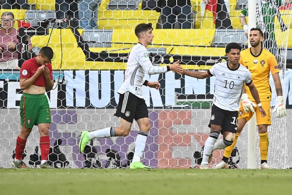 Germany's midfielder Serge Gnabry (2ndR) celebrates their second goal, an own goal scored by Portugal's defender Raphael Guerreiro with Germany's forward Kai Havertz (2ndL) during the UEFA EURO 2020 Group F football match between Portugal and Germany at Allianz Arena in Munich, Germany, on June 19, 2021. (Photo by PHILIPP GUELLAND / POOL / AFP) / The erroneous mention[s] appearing in the metadata of this photo by PHILIPP GUELLAND has been modified in AFP systems in the following manner: [their second goal, an own goal scored by Portugal's defender Raphael Guerreiro] instead of [scoring his team's second goal]. Please immediately remove the erroneous mention[s] from all your online services and delete it (them) from your servers. If you have been authorized by AFP to distribute it (them) to third parties, please ensure that the same actions are carried out by them. Failure to promptly comply with these instructions will entail liability on your part for any continued or post notification usage. Therefore we thank you very much for all your attention and prompt action. We are sorry for the inconvenience this notification may cause and remain at your disposal for any further information you may require.