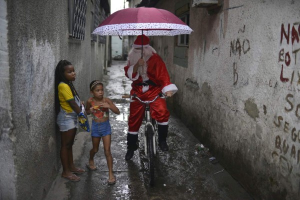 Leandro Souza, 28, who lives in the favela da Mare complex, one of the most violents in Rio de Janeiro, dresses as Santa Claus to distribute gifts to the children of the community in Rio de Janeiro, Brazil on December 17, 2016. / AFP PHOTO / FABIO TEIXEIRA