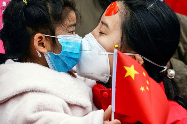 TOPSHOT - A medical staff member kisses her daughter after returning home from Wuhan helping with the COVID-19 coronavirus recovery effort, in Bozhou, in China's eastern Anhui province on April 10, 2020. (Photo by STR / AFP) / China OUT