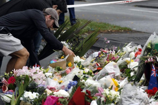 People present floral tributes at a makeshift memorial for victims of the March 15 mosque attacks, in Christchurch on March 17, 2019. - The death toll from horrifying shootings at two mosques in New Zealand rose to 50, police said March 17, as Christchurch residents flocked to memorial sites and churches across the city to lay flowers and mourn the victims. (Photo by Tessa BURROWS / AFP)