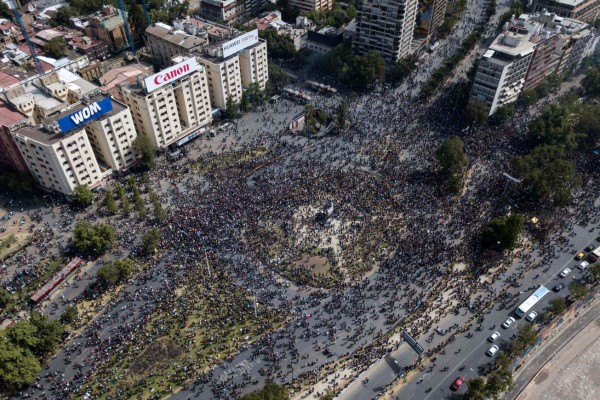 TOPSHOT - Aerial view showing demonstrators in Santiago, on the sixth straight day of street violence which erupted over a now suspended hike in metro ticket prices, on October 23, 2019. - A four-year-old child was killed during the latest round of protests against economic inequality in Chile, raising the death toll from five days of social unrest to 18 as unions launched a general strike on Wednesday. (Photo by JAVIER TORRES / AFP)
