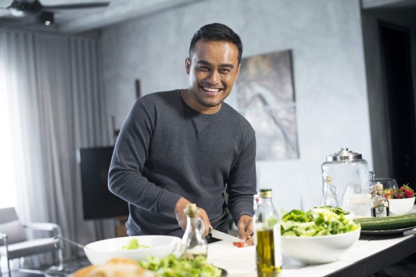 Young Asian man cooking in the kitchen at home.