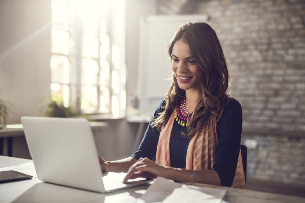 Happy businesswoman sitting in the office and working on computer.