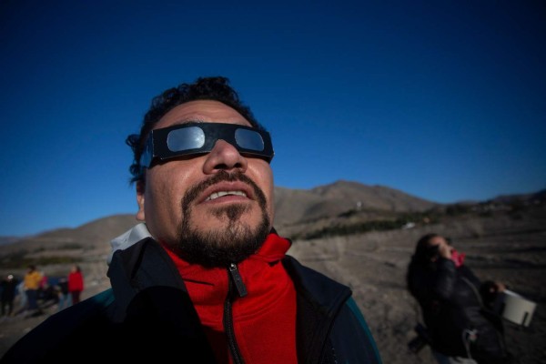 People watch the solar eclipse, from Puclaro, Coquimbo Region, Chile, on July 02, 2019. - Tens of thousands of tourists braced Tuesday for a rare total solar eclipse that was expected to turn day into night along a large swath of Latin America's southern cone, including much of Chile and Argentina. (Photo by CLAUDIO REYES / AFP)