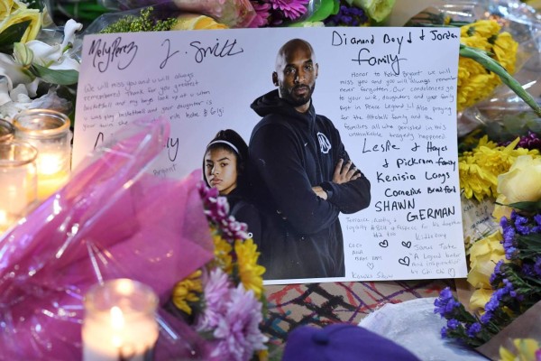A note is seen among flowers and candles at a makeshift memorial as fans mourn the death of NBA legend Kobe Bryant, who was killed along with his daughter and seven others in a helicopter crash on January 26, at LA Live plaza in front of Staples Center in Los Angeles on January 27, 2020. - Federal investigators sifted through the wreckage of the helicopter crash that killed basketball legend Kobe Bryant and eight other people, hoping to find clues to what caused the accident that stunned the world. (Photo by Robyn Beck / AFP)