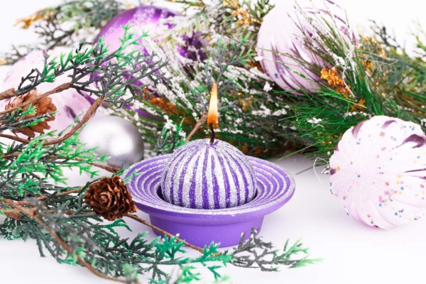 Christmas pink balls, candle and fir tree on gray background.