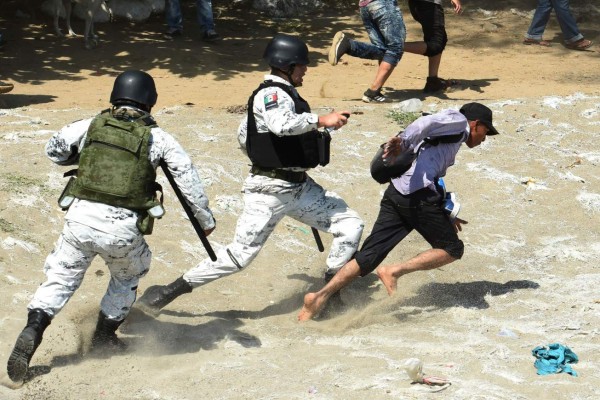 TOPSHOT - A Central American migrant - part of a caravan of mostly Hondurans travelling in caravan to the US- is tackled by a member of Mexico's National Guard after crossing the Suichate River, the natural border between Tecun Uman in Guatemala and Ciudad Hidalgo in Mexico, on January 20, 2020. - Hundreds of Central Americans from a new migrant caravan tried to enter Mexico by force Monday by crossing the river that divides the country from Guatemala, prompting the National Guard to fire tear gas, an AFP correspondent said. (Photo by ISAAC GUZMAN / AFP)