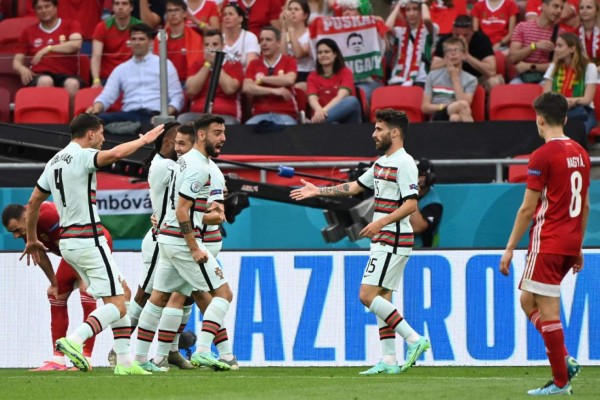 Portugal's players celebrate their opening goal scored by Portugal's defender Raphael Guerreiro during the UEFA EURO 2020 Group F football match between Hungary and Portugal at the Puskas Arena in Budapest on June 15, 2021. (Photo by Attila KISBENEDEK / POOL / AFP)