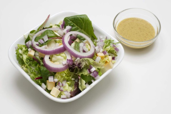 Lettuce salad with mustard vinaigrette dressing in small glass bowl