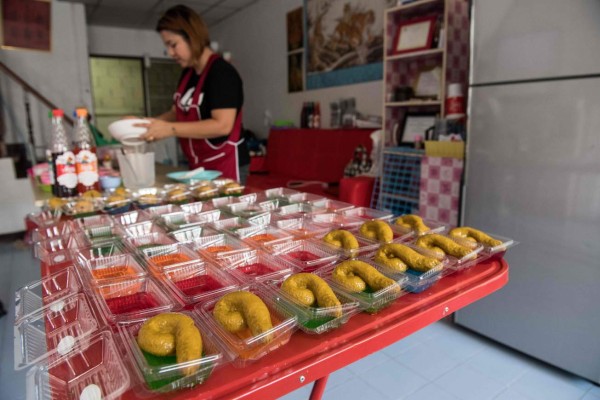 This picture taken on June 19, 2017 shows Wilaiwan Mee-Nguen filling moulds for an online order of desserts in the shape of dog poop at her home in Bangkok.It might turn some stomachs, but a dessert-maker in Thailand has been flooded with orders ever since she started crafting gelatinous sweets into the shape -- and colour -- of dog poop. / AFP PHOTO / Roberto SCHMIDT