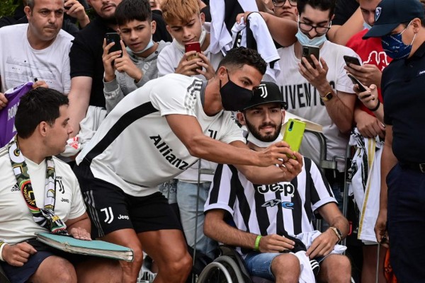 Juventus' Portuguese forward Cristiano Ronaldo poses with fans as arrives for his medical examination at the Juventus medical center in Turin, on July 26, 2021. (Photo by MIGUEL MEDINA / AFP)