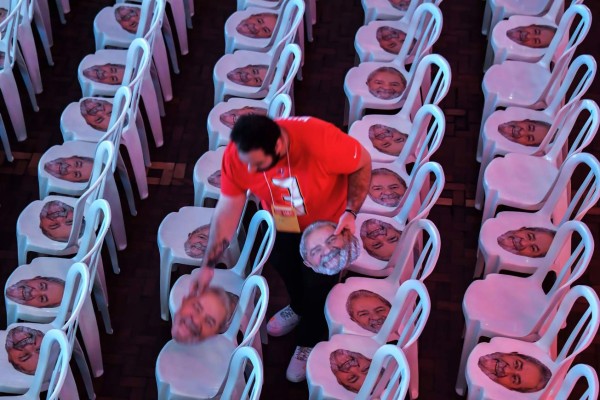 An man places masks of former Brazilian president Luiz Inacio Lula da Silva on chairs, before the national convention of the Workers Party (PT), in Sao Paulo, Brazil on August 04, 2018.Brazil's presidential election, starting with a first round on October 7, is seen as the most unpredictable in decades. The leftist Workers' Party that Lula da Silva founded is due to nominate him as its candidate. After that, it will be up to the country's top courts to decide whether he can be on the ballot. / AFP PHOTO / NELSON ALMEIDA