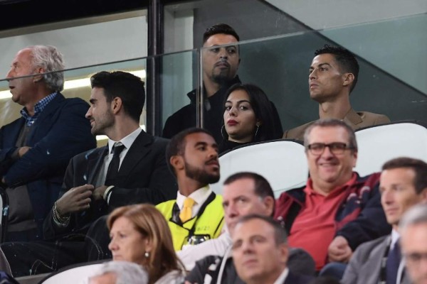 Suspended Juventus' Portuguese forward Cristiano Ronaldo (R) and his girlfriend Spanish model Georgina Rodriguez (C) watch the UEFA Champions League group H football match between Juventus and Young Boys from the tribune, on October 2, 2018 at the Juventus stadium in Turin. / AFP PHOTO / Marco BERTORELLO
