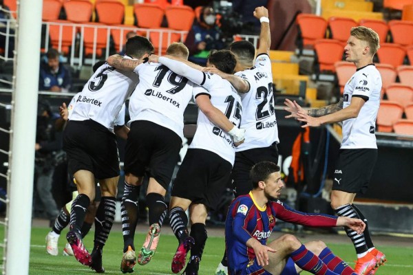 Valencia's Brazilian defender Gabriel Paulista (L) celebrates his goal with teammates during the Spanish League football match between Valencia and Barcelona at the Mestalla stadium in Valencia on May 2, 2021. (Photo by JOSE JORDAN / AFP)