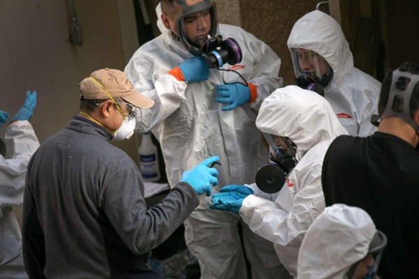 KIRKLAND, WASHINGTON - MARCH 11: A cleaning crew disinfects and removes protective clothing after exiting the Life Care Center on March 11, 2020 in Kirkland, Washington. Most of the coronavirus deaths in Washington State have been linked to the nursing home. John Moore/Getty Images/AFP== FOR NEWSPAPERS, INTERNET, TELCOS & TELEVISION USE ONLY ==