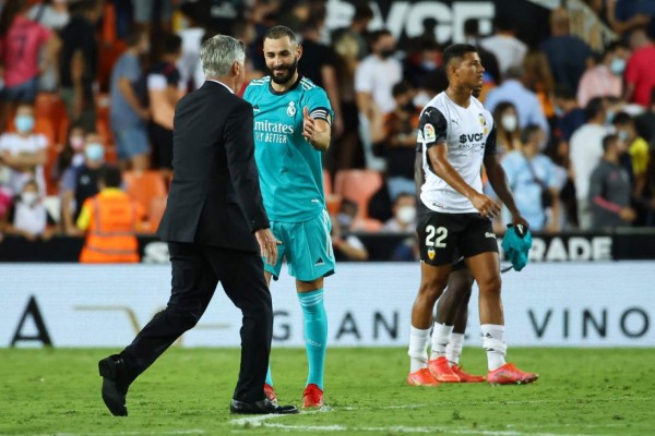 Real Madrid's Italian coach Carlo Ancelotti (L) and Real Madrid's French forward Karim Benzema celebrate their win at the end of the Spanish League football match between Valencia CF and Real Madrid CF at the Mestalla stadium in Valencia on September 19, 2021. (Photo by JOSE JORDAN / AFP)