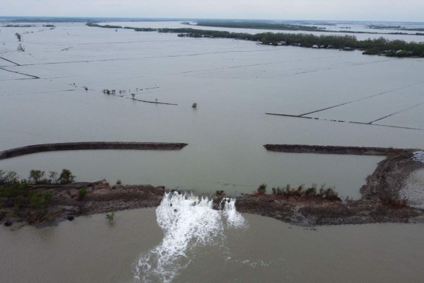 An aerial view shows water from a flooded crab farming area (top) break through a damaged dam following the landfall of cyclone Amphan in Burigoalini on May 21, 2020. - At least 84 people died as the fiercest cyclone to hit parts of Bangladesh and eastern India this century sent trees flying and flattened houses, with millions crammed into shelters despite the risk of coronavirus. (Photo by Munir uz Zaman / AFP)