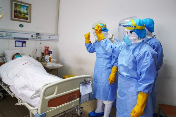 This photo taken on January 28, 2020 shows medical staff members cheering up a patient infected by the novel coronavirus in an isolation ward at a hospital in Zouping in China's easter Shandong province. - China faced deepening isolation over its coronavirus epidemic on February 1 as the death toll soared to 259, with the United States leading a growing list of nations to impose extraordinary Chinese travel bans. (Photo by STR / AFP) / China OUT
