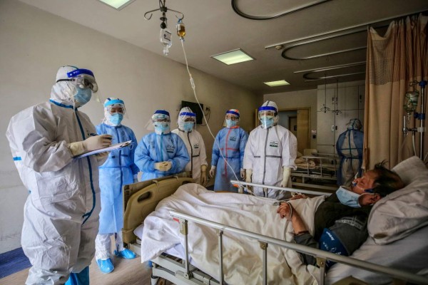 Medical staff speak with a patient infected by the COVID-19 coronavirus at Red Cross Hospital in Wuhan in China's central Hubei province on March 10, 2020. - Chinese President Xi Jinping said on March 10 that Wuhan has turned the tide against the deadly coronavirus outbreak, as he paid his first visit to the city at the heart of the global epidemic. (Photo by STR / AFP) / China OUT