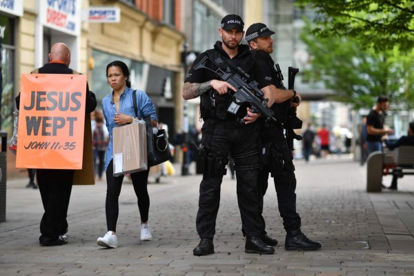Armed police stand secure a street in central Manchester, northwest England, on May 24, 2017, following the May 22 terror attack at the Manchester Arena.Police on Tuesday named Salman Abedi -- reportedly British-born of Libyan descent -- as the suspect behind a suicide bombing that ripped into young fans at an Ariana Grande concert at the Manchester Arena on May 22, as the Islamic State group claimed responsibility for the carnage. / AFP PHOTO / Ben STANSALL