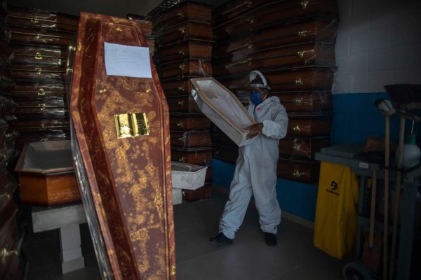 TOPSHOT - A gravedigger wearing personal protective equipment organizes coffins at the Public Cemetery of Duque de Caxias, in Rio de Janeiro state, Brazil, on May 27, 2020. (Photo by Mauro Pimentel / AFP)
