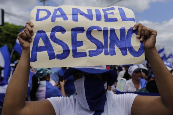 A demonstrator holds a sign reading ' Daniel (Ortega) murderer', during a march against Nicaraguan President Daniel Ortega's government in Managua, on September 2, 2018. At least two people were injured on Sunday, when alleged paramilitaries fired against an opposition march, which ended up in violence in eastern Managua. / AFP PHOTO / INTI OCON