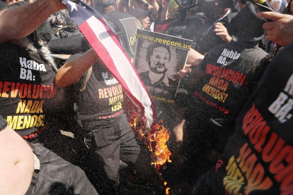 CLEVELAND, OH - JULY 20: A group tries to burn an American Flag as police move in near the sight of the Republican National Convention (RNC) in downtown Cleveland on the third day of the convention on July 20, 2016 in Cleveland, Ohio. Many people have stayed away from downtown due to road closures and the fear of violence. An estimated 50,000 people are expected in Cleveland, including hundreds of protesters and members of the media. The four-day Republican National Convention kicked off on July 18. Spencer Platt/Getty Images/AFP== FOR NEWSPAPERS, INTERNET, TELCOS & TELEVISION USE ONLY ==