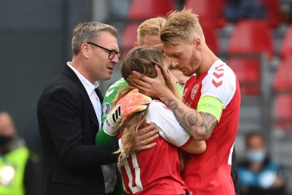 Sabrina Kvist Jensen (C), partner of Denmark's midfielder Christian Eriksen, is embraced by Denmark's defender Simon Kjaer (R) as she reacts after Eriksen collapsed during the UEFA EURO 2020 Group B football match between Denmark and Finland at the Parken Stadium in Copenhagen on June 12, 2021. (Photo by Jonathan NACKSTRAND / various sources / AFP)