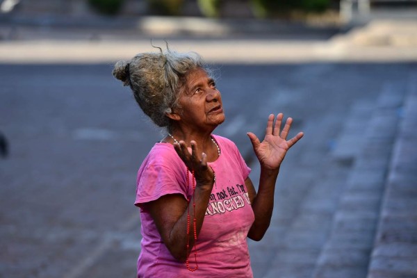An elderly woman prays for those infected with the new coronavirus at the central square in Tegucigalpa, on March 25, 2020. - Authorities have confirmed 52 cases of COVID-19 in the country so far. (Photo by ORLANDO SIERRA / AFP)