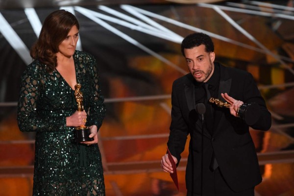 US director Ezra Edelman (R) delivers a speech on stage next to producer Caroline Waterlow after they won Best Documentary Feature award for 'O.J. Made In America' at the 89th Oscars on February 26, 2017 in Hollywood, California. / AFP PHOTO / Mark RALSTON