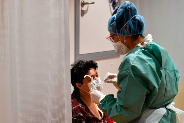 A medical staff examines a patient at the hospital screening unit of the CHU Pellegrin in Bordeaux, southwestern France on March 9, 2020. - The CHU Pellegrin in Bordeaux has opened a screening unit for the novel coronavirus where patients are examined in a box by a team made up of doctors and nurses who take samples, before senidng them the virology laboratory to confirm or not the infection by the novel coronavirus.With 1,191 recorded cases and 21 deaths, France is the second-worst affected European country after neighbour Italy, which has imposed a sweeping lockdown on the most hard-hit northern regions. (Photo by GEORGES GOBET / AFP)